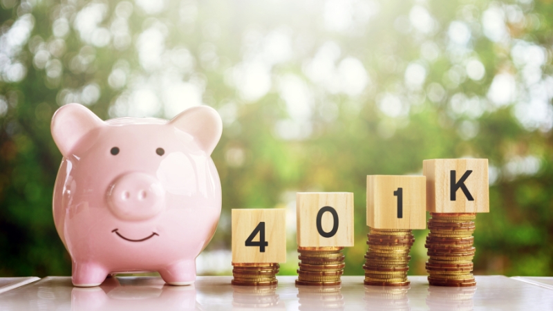 A pink piggy bank sits next to stacked coins labeled "401K," showing the concept of saving for retirement