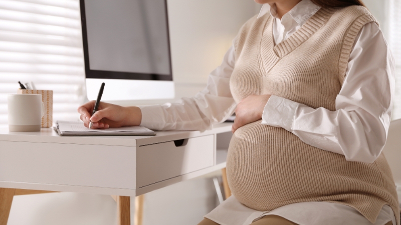 A pregnant freelancer works at her desk while planning for maternity leave