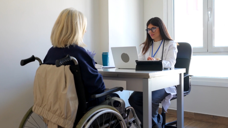 Doctor meeting with a woman in a wheelchair during a disability insurance consultation