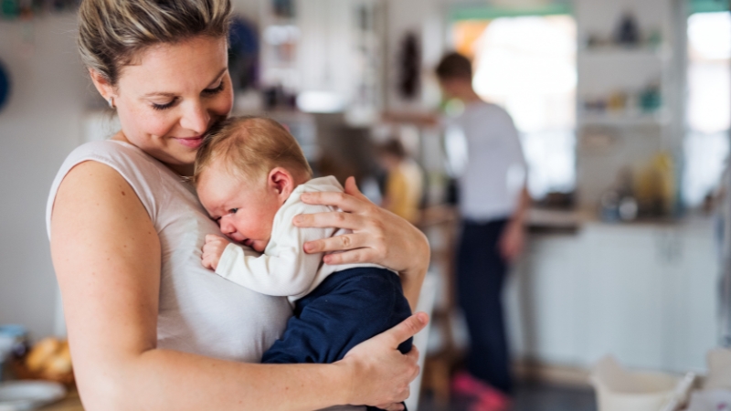 Mother holds her baby at home while relying on voluntary paid family leave insurance in the US